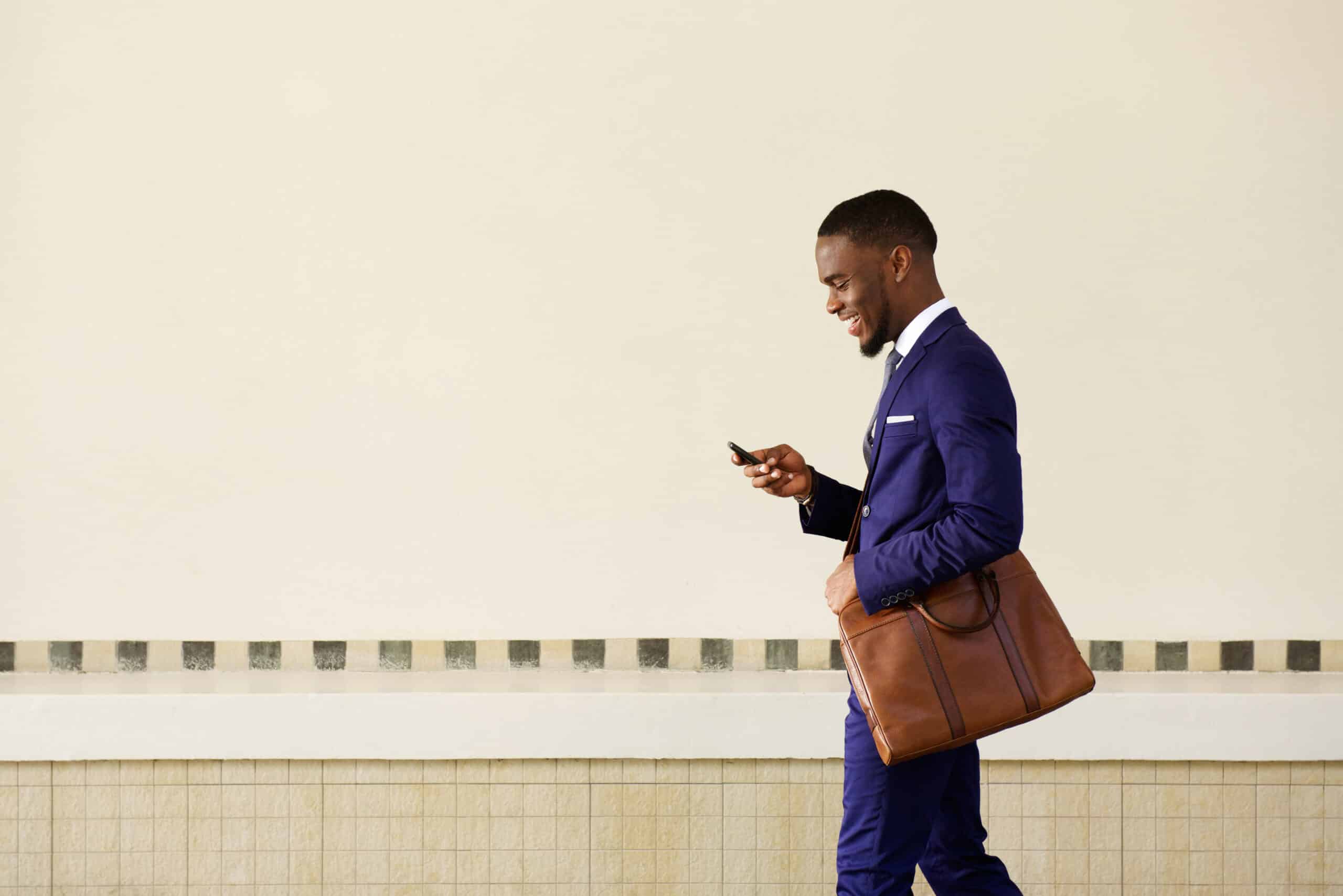 Professional walking while checking a smartphone, representing real-time SMS communication used to deliver timely updates, promotions, and customer engagement messages.