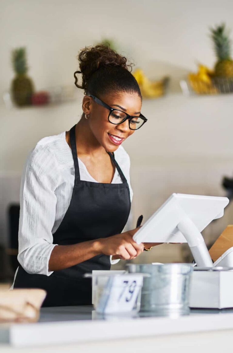 Retail staff member using a tablet at the counter, representing how digital membership programs simplify sign-ups, lookups, and member management without physical cards.