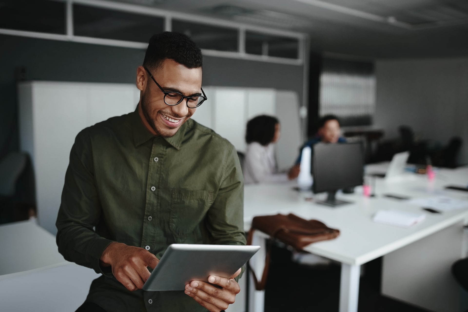 Employee reviewing analytics on a tablet in an office environment, representing real-time insights and performance tracking for a digital wallet loyalty or engagement program.