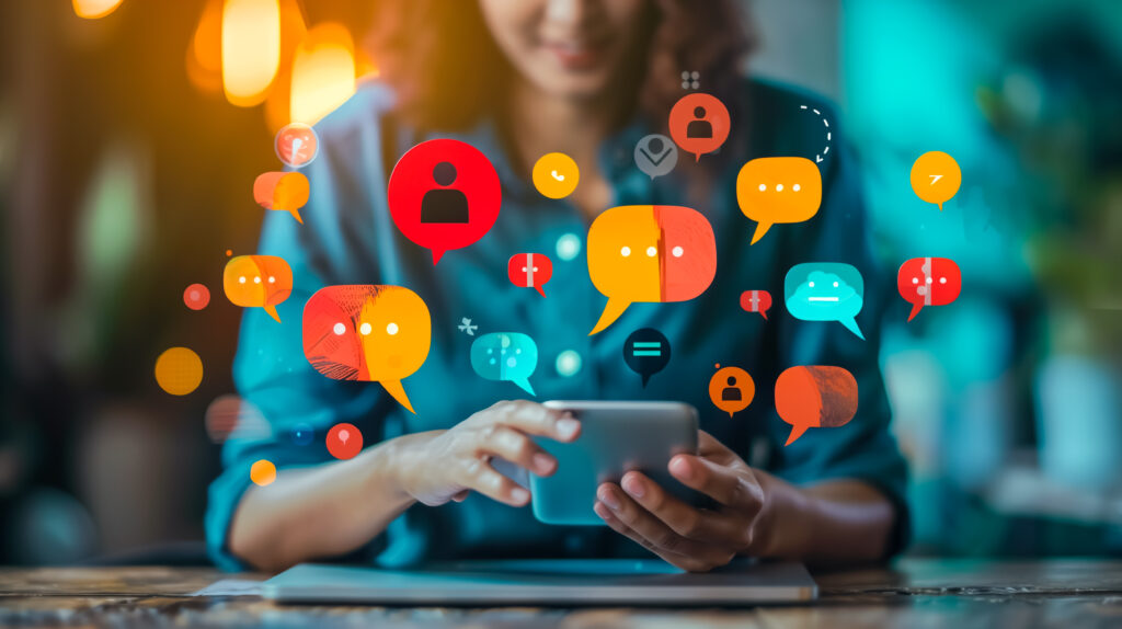Person using a smartphone with colorful chat bubbles, message icons, and user profile symbols floating around, representing online communication, social media engagement, and digital interaction.