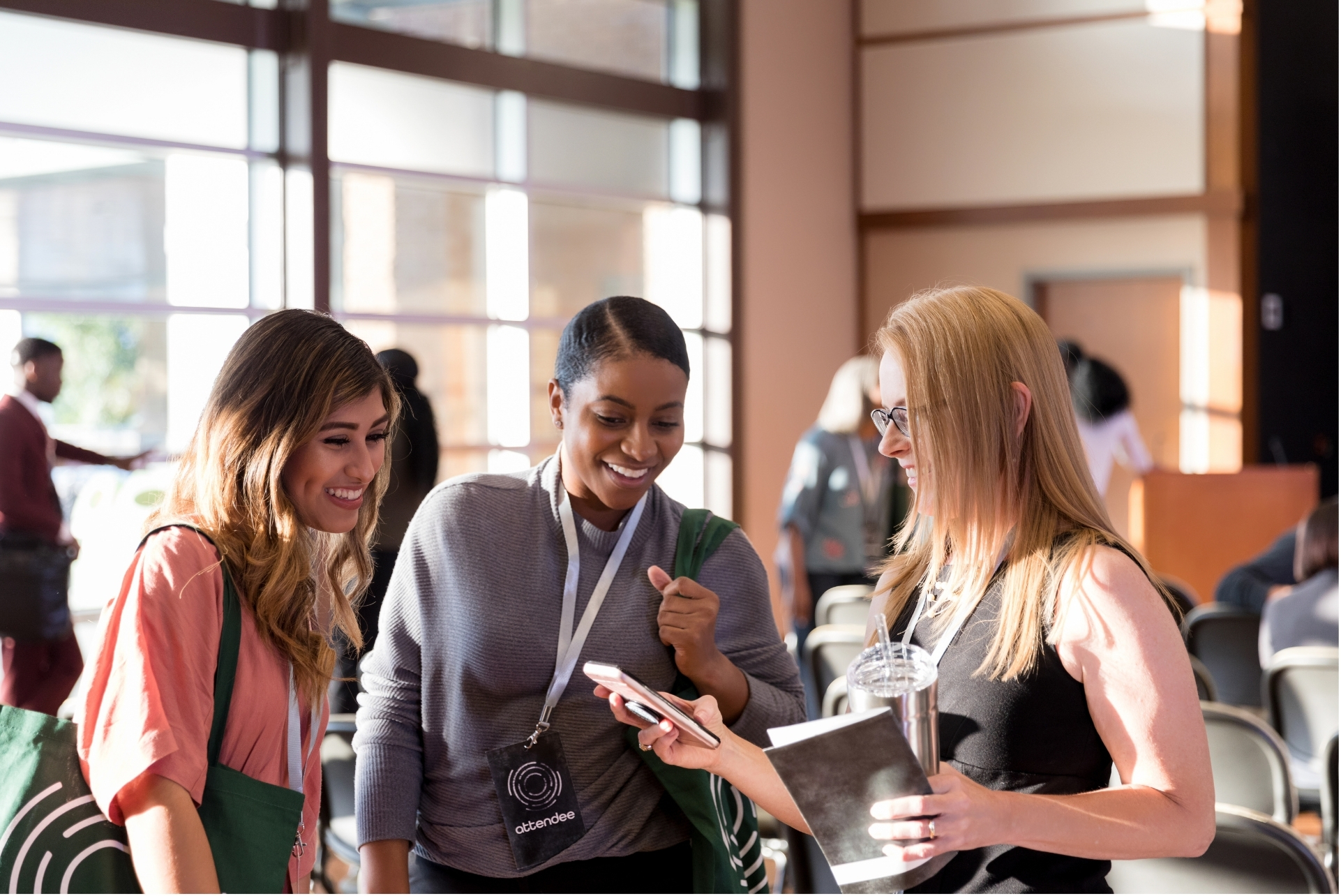 Group of people viewing a smartphone together, representing shared access to digital wallet passes for memberships, rewards, or personalized experiences.