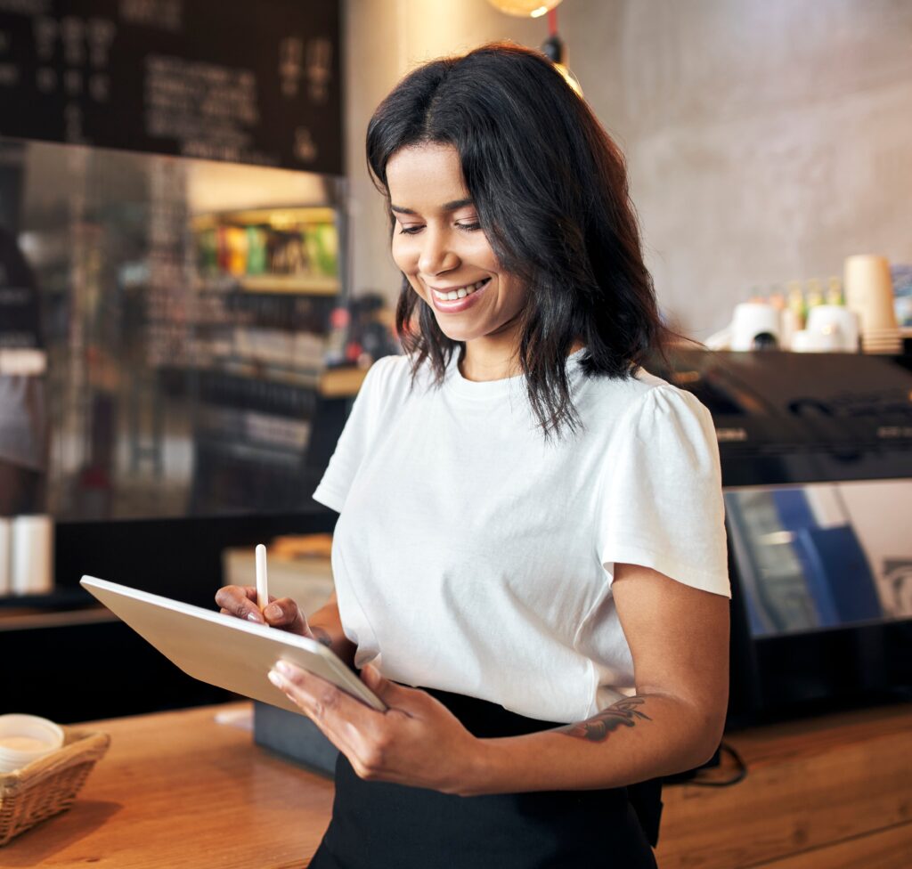 Retail employee smiling while using a tablet in-store, representing how staff can manage or support customer engagement through digital wallet programs.