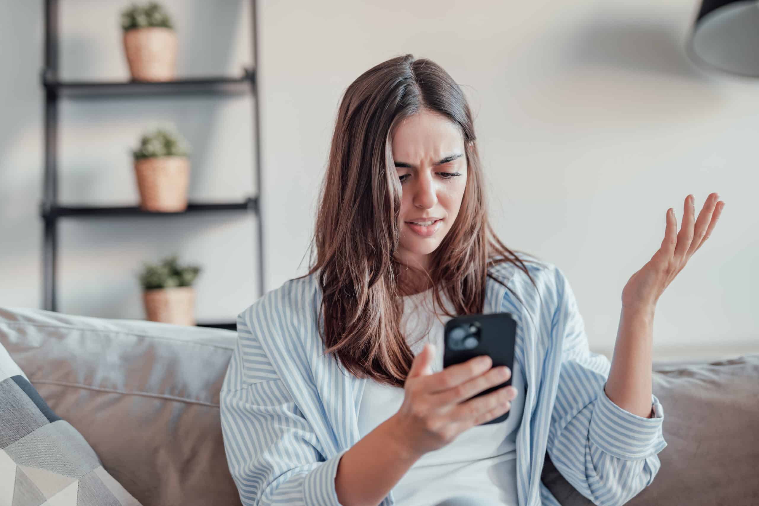 A frustrated customer looking at a smartphone while searching for important account information, illustrating common customer support and self-service challenges.